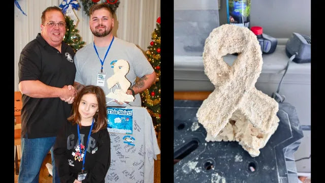 David Chandler presenting a hand-sculpted reef rock cancer ribbon alongside a young girl at a reef show